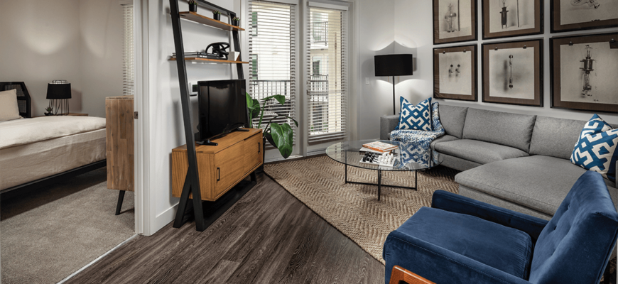 living room leading into the bedroom with a blue chair on the right, shelf on the left